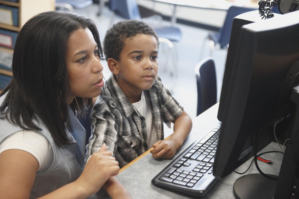 Teacher And Male Student Looking At Computer