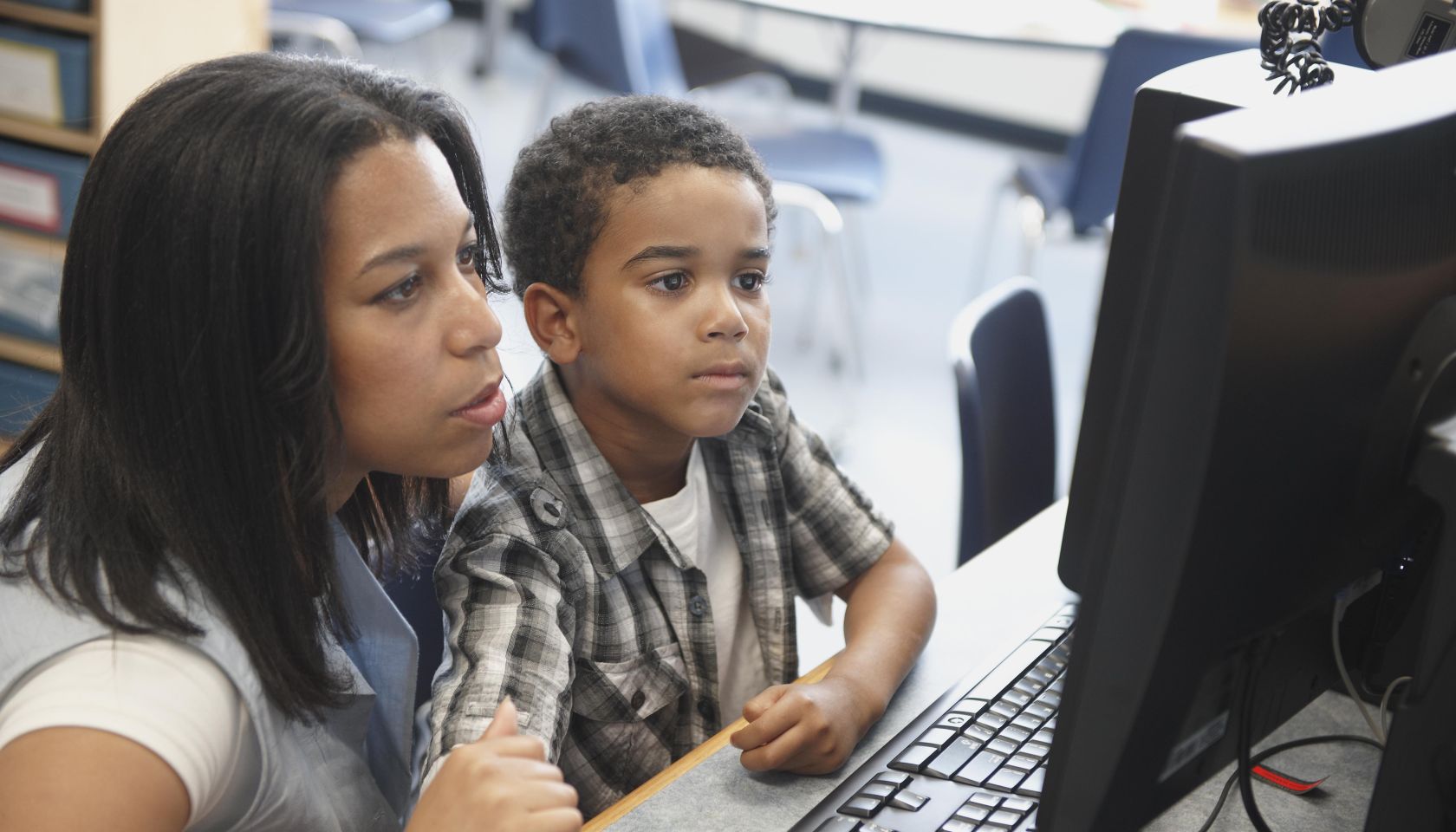 Teacher And Male Student Looking At Computer