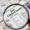 Magnifying glass over a newspaper classified section with "Job Opportunity" text