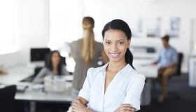 An attractive ethnic business woman smiling confidently at the camera as she stands in an office