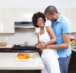 Man embracing woman preparing vegetables