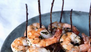Grilled shrimp skewered with rosemary twigs on stoneware platter