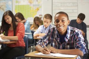 Portrait Of Male Pupil Studying At Desk In Classroom