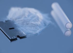 Close up of cocaine and blow tube on blue background