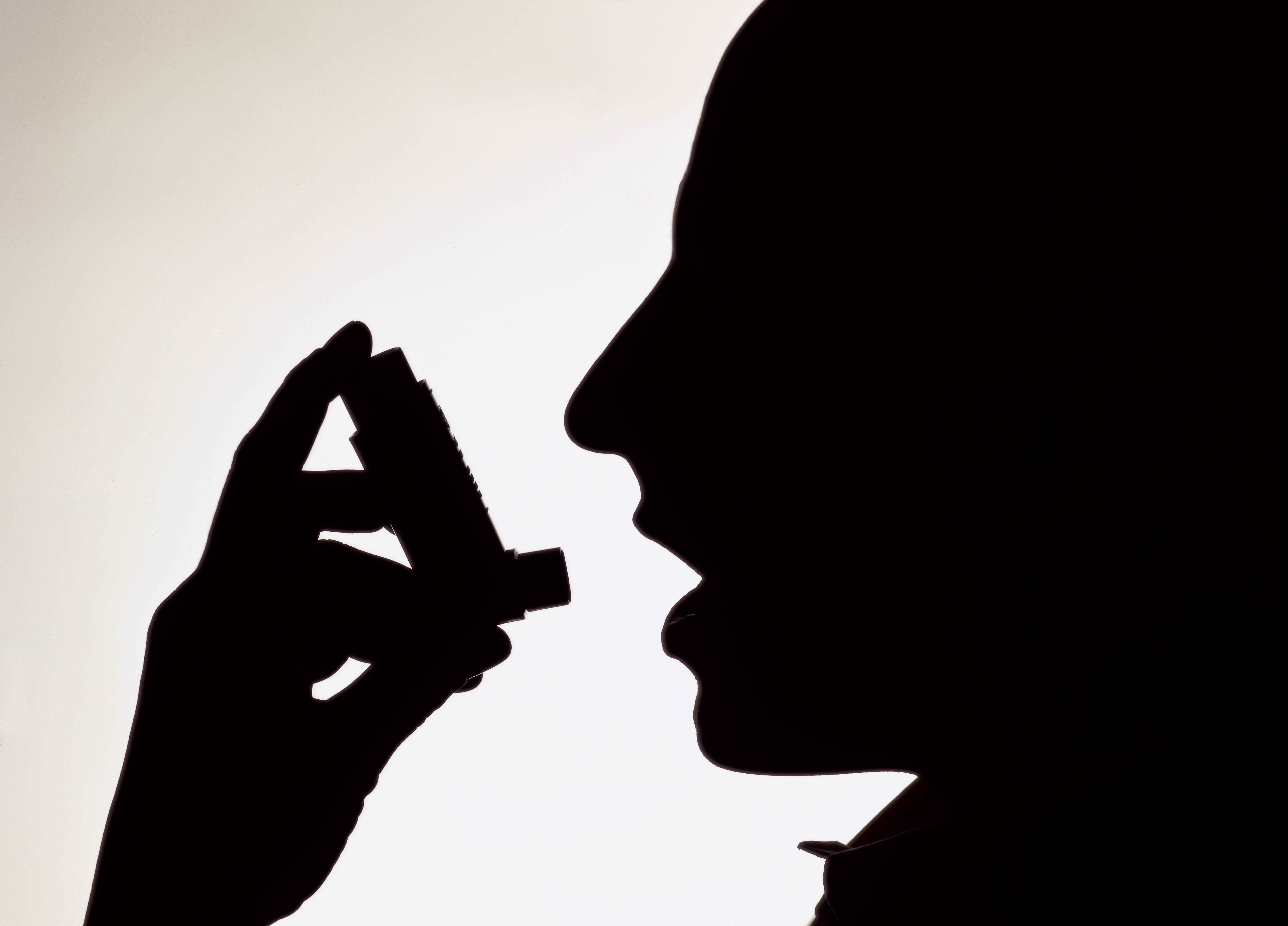 Side profile silhouette of a person using an inhaler
