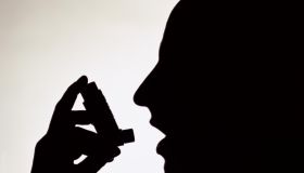 Side profile silhouette of a person using an inhaler