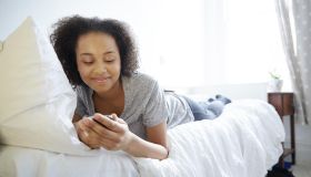 Teenage girl laying on a bed using technology