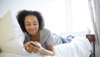 Teenage girl laying on a bed using technology