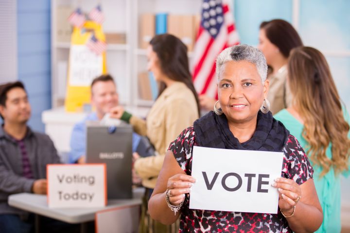 Voters register, voting in USA elections. Woman holds 'Vote' sign.