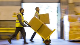 Workers carting boxes in warehouse