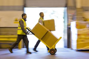 Workers carting boxes in warehouse