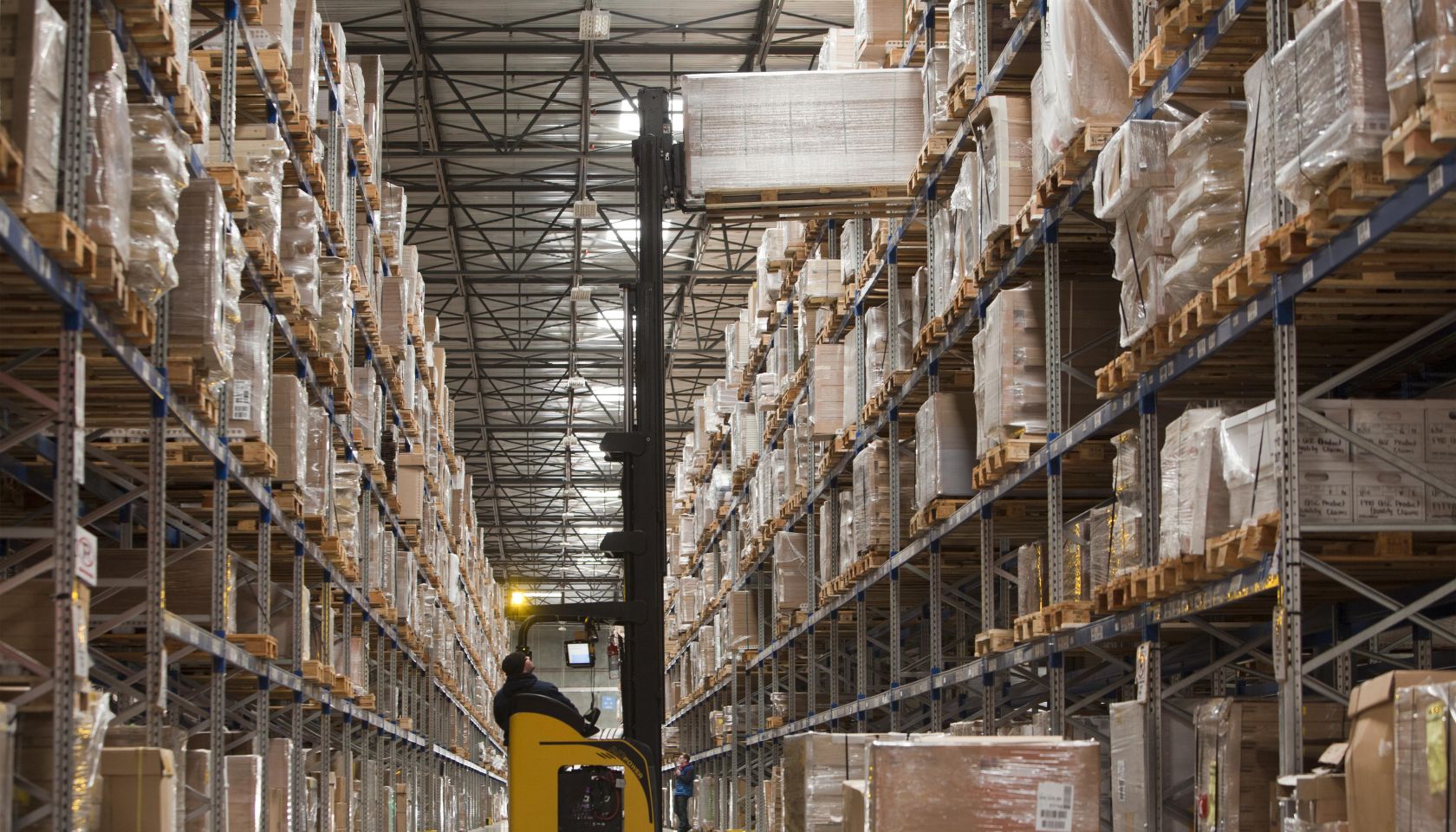 Warehouse worker lifting a pallet of boxes