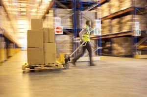 Blurred view of worker carting boxes in warehouse