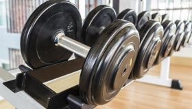 Many black dumbbell lined up in a fitness room.