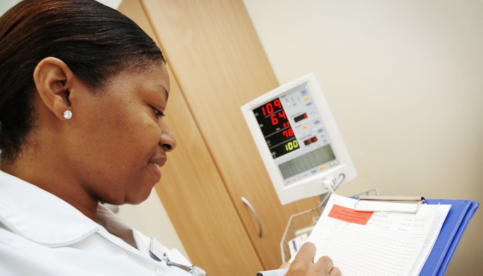 Nurse in white uniform writing updates to her patients records