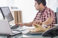 Mixed race businessman eating and working at desk