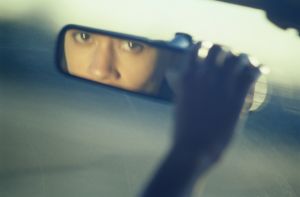 Woman Looking into a Rear-View Mirror