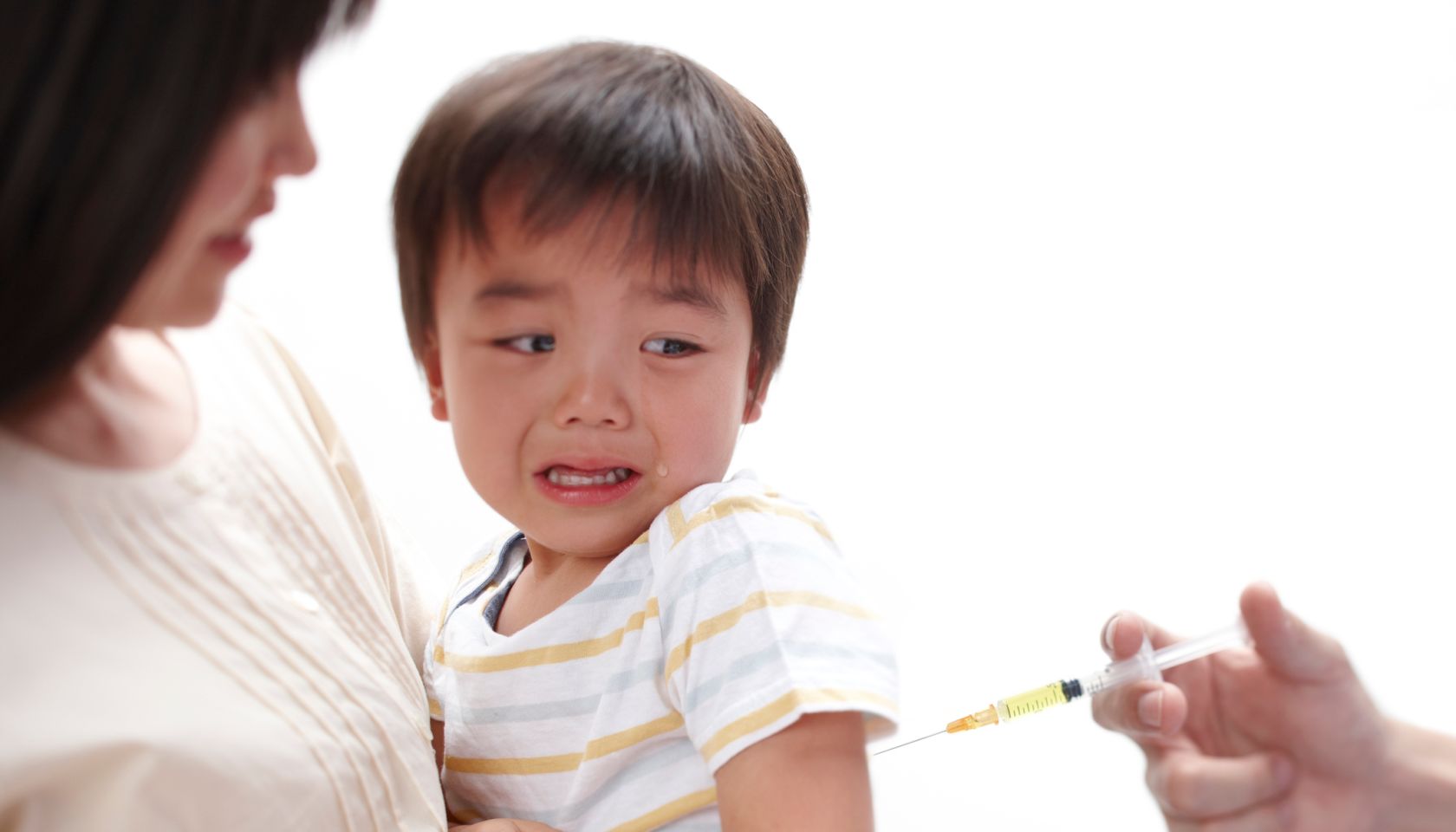 Mother holds her crying baby boy while he gets a vaccination