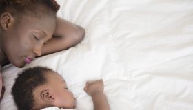 Black mother and son sleeping on bed