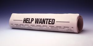 Rolled newspaper titled help wanted, close-up