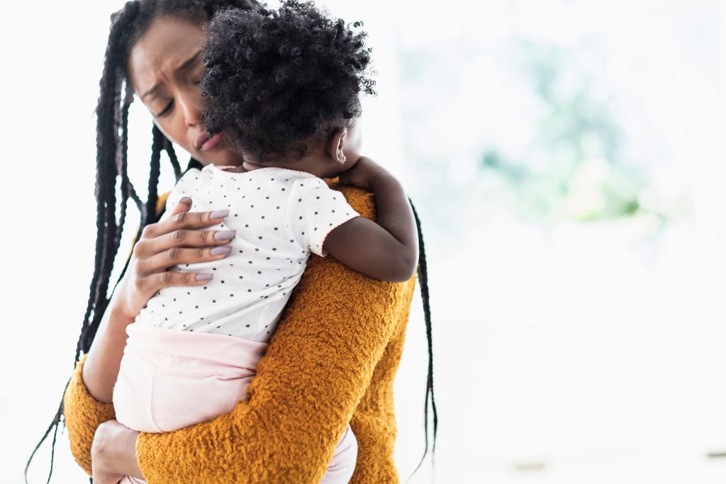 Black woman holding and comforting baby daughter