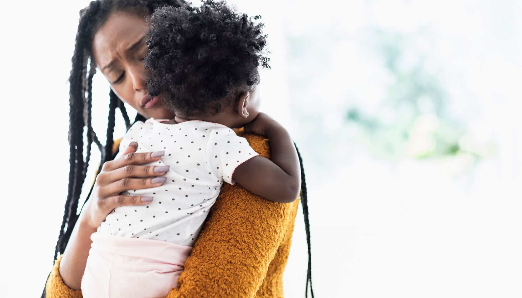 Black woman holding and comforting baby daughter