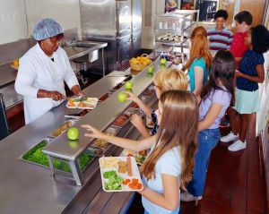 Woman serving food to schoolchildren (10-13) in cafeteria