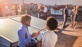 Happy African American man toasting with his female colleague during a party on a roof.