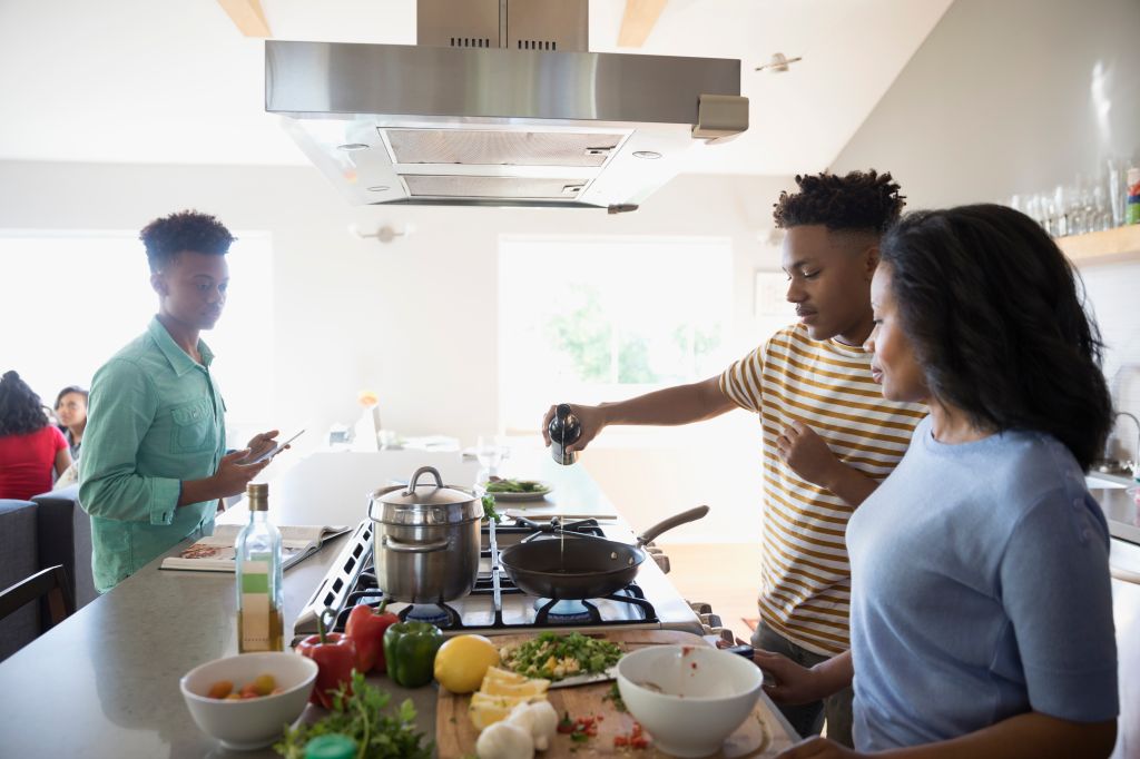 African American mother and teenage sons cooking in kitchen