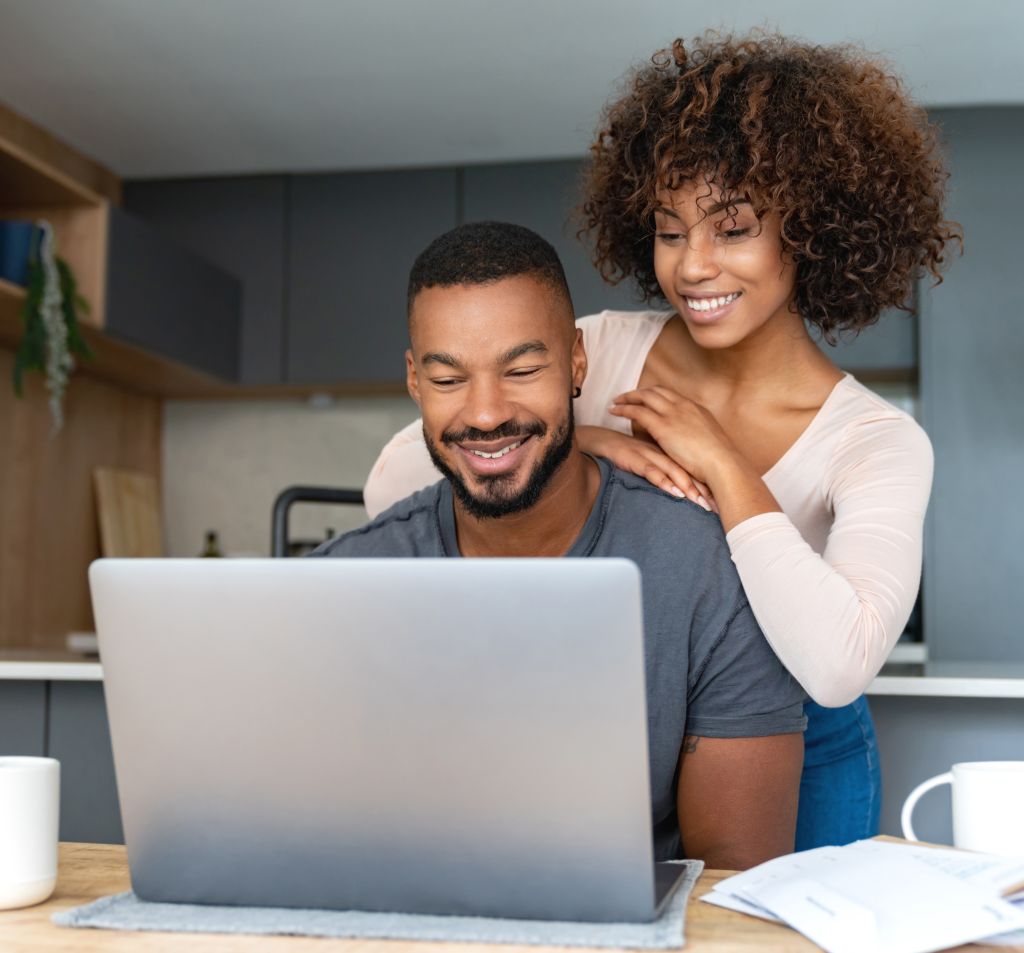 Black couple paying bills online at home