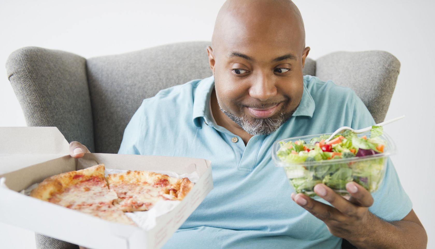 African American deciding between salad and pizza
