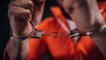 Man prisoner in orange jumpsuit wearing handcuffs