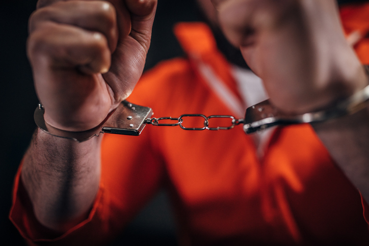 Man prisoner in orange jumpsuit wearing handcuffs