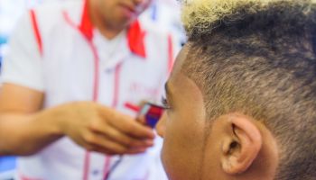 Hairdresser cutting teenage boys hair in barbershop