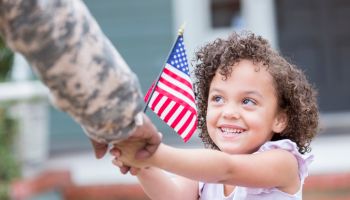 Adorable little girl holds her military dad's hand
