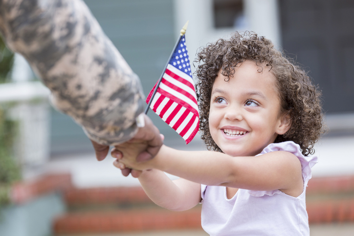 Adorable little girl holds her military dad's hand