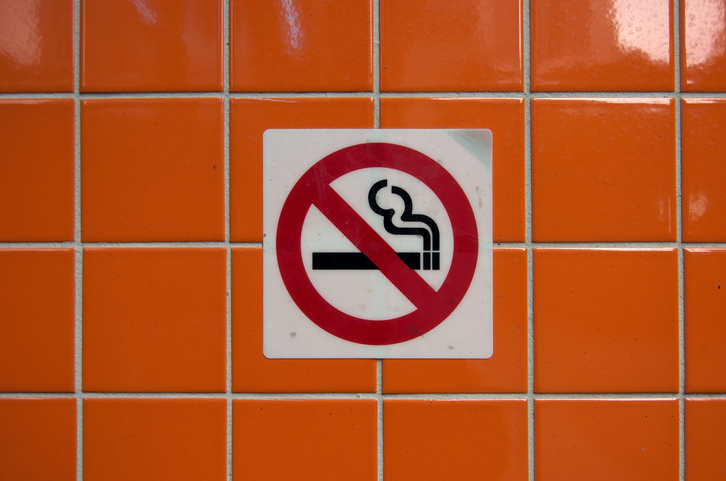 'No smoking' sign on a wall with glossy orange tiles