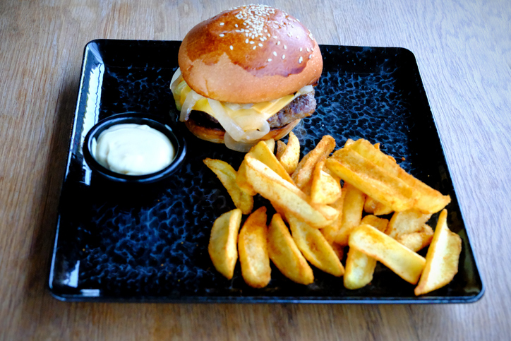 A hamburger, french fries and mayonnaise sauce served on a black plate in a restaurant.