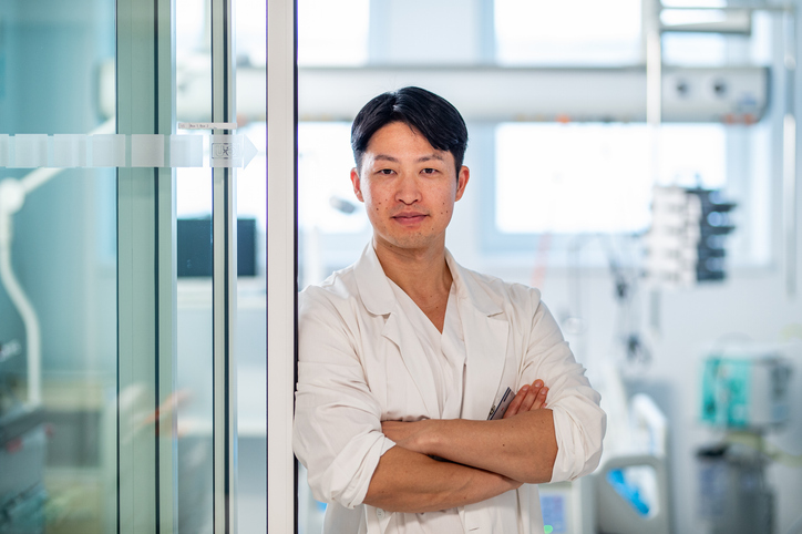 Portrait of handsome asian doctor standing in hospital corridor.
