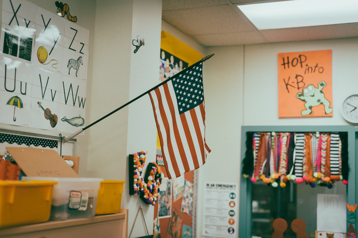 Toned photo of proudly display of American flag in wall mouth flagpole in kindergarten classroom in public Texas elementary school