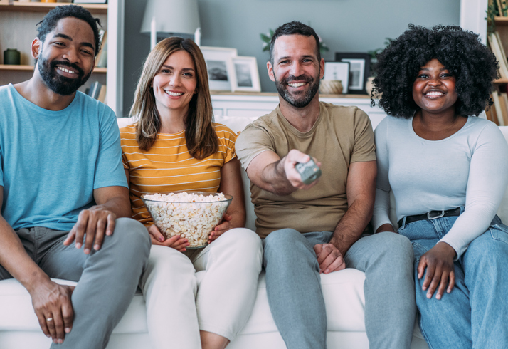 Cheerful friends watching TV at home.