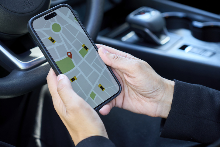 Person checking ride-sharing app on smartphone inside car