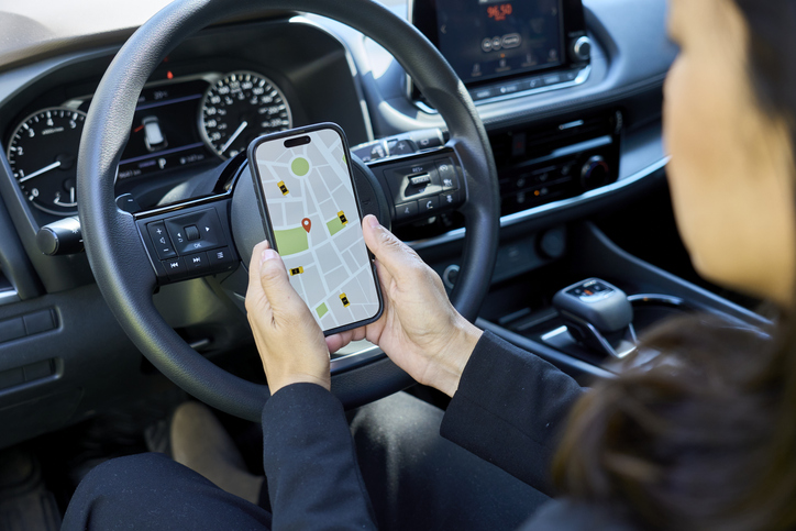 Driver checking ride-sharing application on smartphone in car