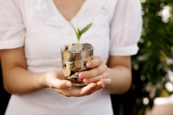 Investment Growth Concept - Hands Holding Coins Jar with Plant Sprout for Retirement Savings Planning