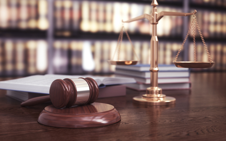 Judge Gavel and Scales of Justice on Desk in Law Library Representing Legal System