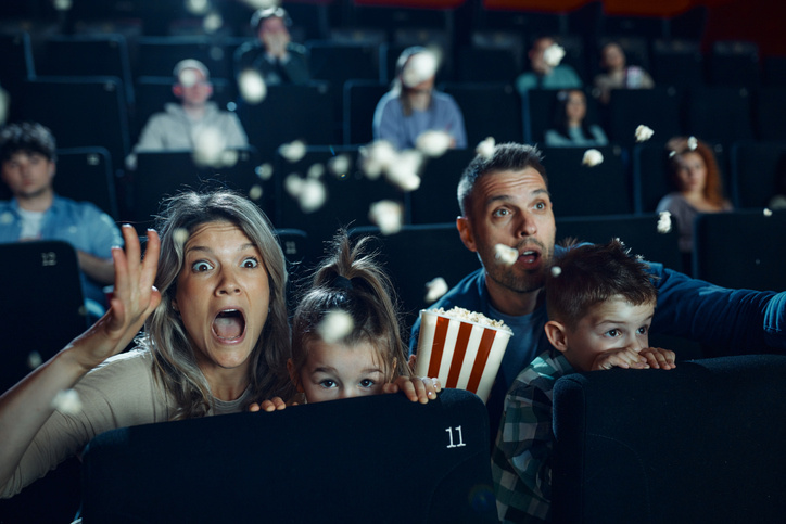 Fearful family watching a horror movie in cinema.