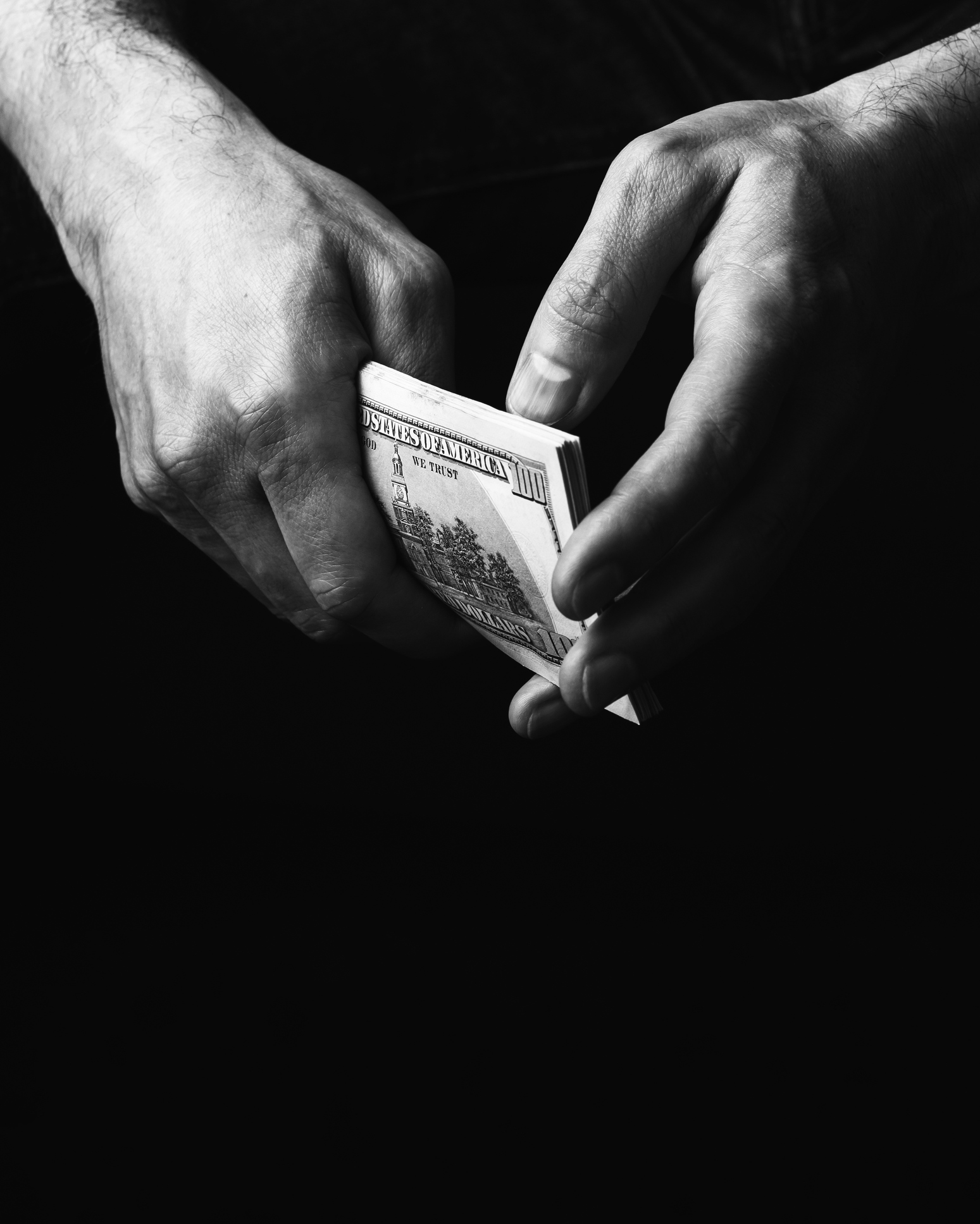 Man hands holding stack US dollar bills against black background. Concept of finance, wealth, business, corruption