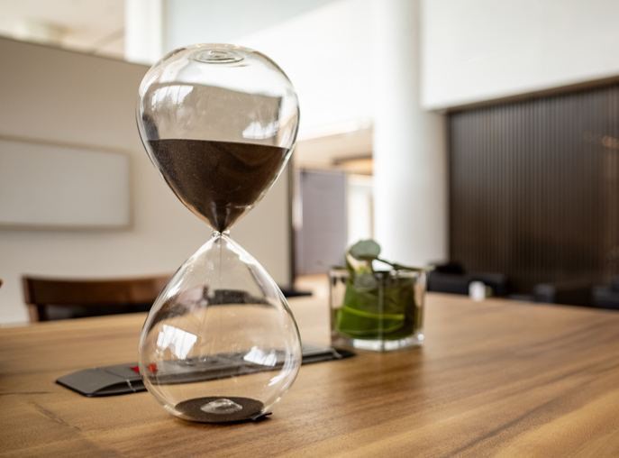 Modern Glass Hourglass with Black Sand on a Wooden Office Table