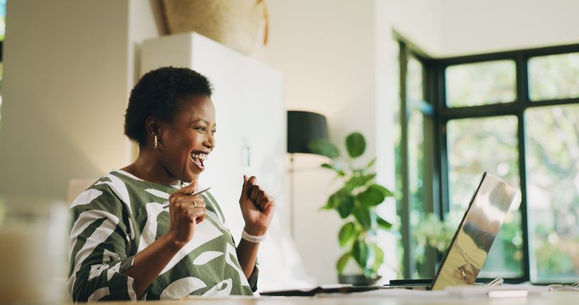 Budgeting, black woman and celebration with laptop in home for loan approval, rebate and savings. Excited, person and technology in house for financial planning, positive credit score and tax return