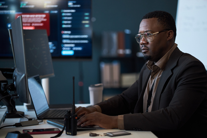Black Adult Man Monitoring Cybersecurity Data in Control Room